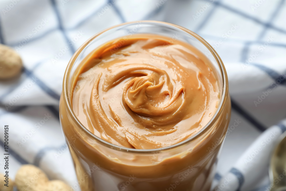 Jar with creamy peanut butter on napkin