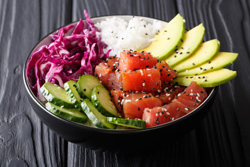 Organic food: tuna poke bowl with rice, fresh cucumbers, red cabbage and avocado close-up. horizontal