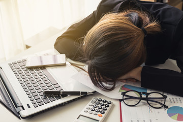 Overworked and tired businesswoman sleeping on laptop in workplace