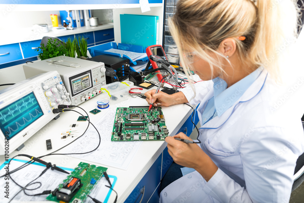 Female electronic engineer testing computer motherboard in laboratory - obrazy, fototapety, plakaty 