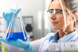 © Scanrail - Young attractive female scientist holding a flask with blue liquid substance in the laboratory