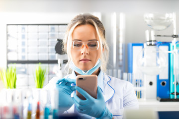 Young attractive woman scientist using smartphone in the laboratory