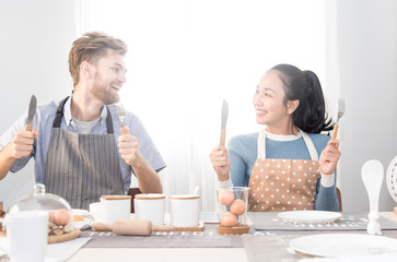 Young couple embrace of love  in the kitchen at home .Caucasian man and asian woman are loving couple cooking together in the kitchen