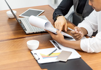 Closed up of . Two successful and confident Business partners meeting in formal wear discussing something with worksheet ,laptop,tablet and cell phone on table work in the office