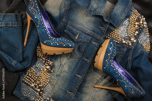Fotografija Shoes and jacket from denim fabric inlaid rhinestones lying on a black silk