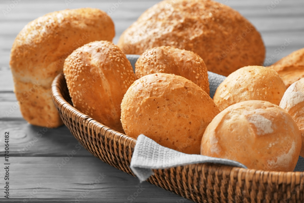 Wicker basket and delicious bread on wooden table