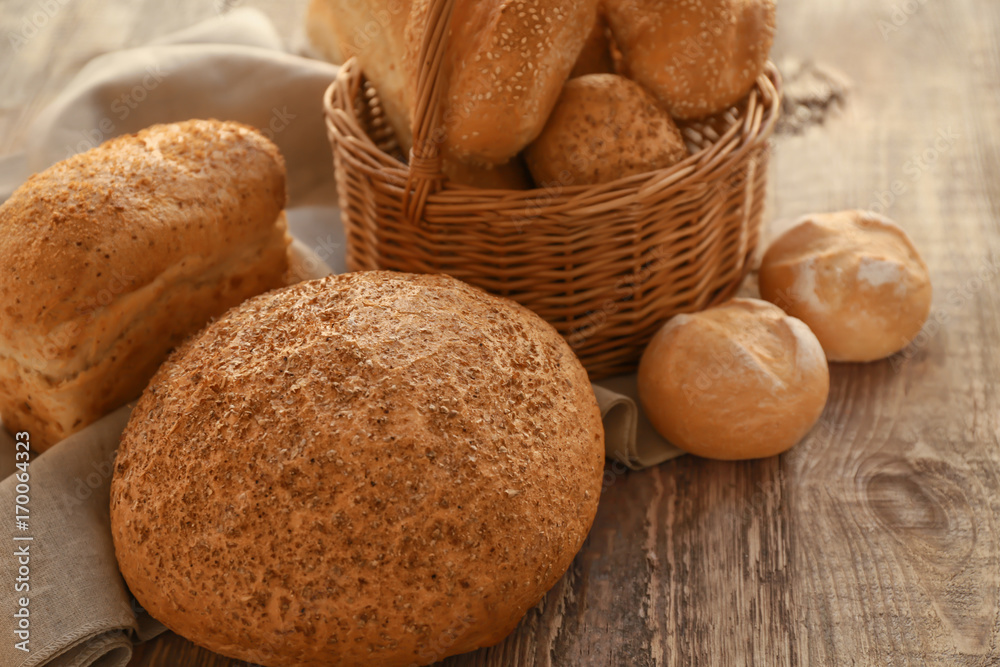 Beautiful composition with wicker basket and delicious bread on wooden table