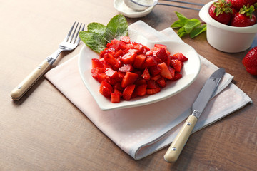 Delicious sliced strawberry in heart shaped plate on wooden table