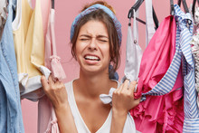 Stressed Unhappy Young European Female Touching Stylish Clothes And Crying Out Loud Because She Can't Afford Any Of Them. Frustrated Girl Having Sad And Painful Look As She Has Nothing To Wear