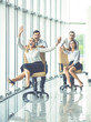 © realstock1 - The four business people ride on chairs in the office hall