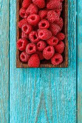 Fresh raspberry in a wooden plate. Photo with copyspace