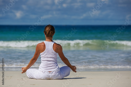 Fotografia Caucasian woman practicing yoga at seashore of tropic ocean