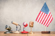 Retro microphones for press conference or interview and USA flag on wooden desk front old concrete wall background. Vintage style filtered photo