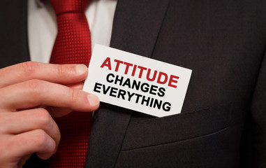 Businessman putting a card with text Attitude Changes Everything in the pocket