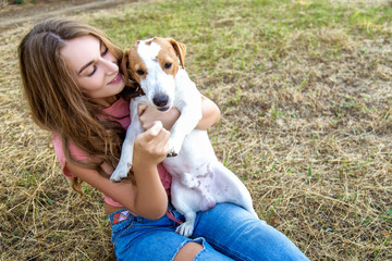 Wall Mural - Cute girl is playing with her dog in the  park