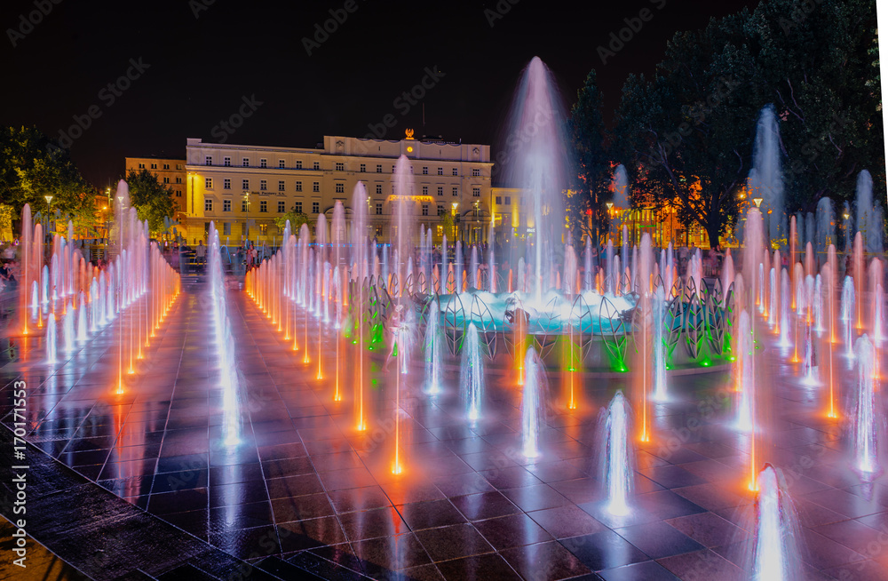 Night colorful fountain show inLublin park. Vivid color fountain water - obrazy, fototapety, plakaty 