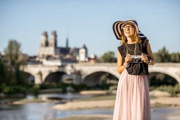 Wall Mural - Young woman tourist standing on the beautiful cityscape background during the sunset in Orleans city, France