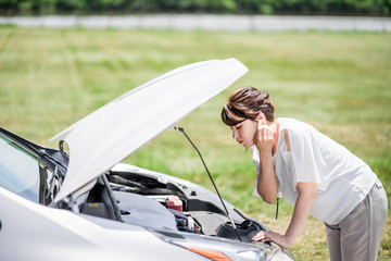 young woman checking under the hood.