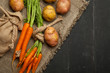 Raw potatoes and carrots on a black wooden background