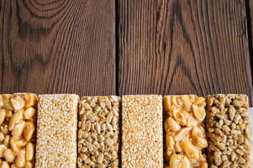 Snacks  - mix of energy bars with peanut, sesame and sunflower seeds on a wooden background