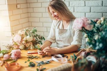 Wall Mural - Florist at work: pretty young blond woman making fashion modern bouquet of different flowers