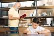 © zinkevych - Smiling schoolboy doing homework while his grandfather reading