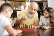 © zinkevych - Little girl watching her brother and grandfather play chess