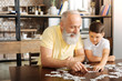 © zinkevych - Happy grandfather doing jigsaw puzzle together with grandson