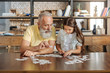 © zinkevych - Grandfather and granddaughter being immersed into doing jigsaw puzzle