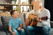 © zinkevych - Loving grandfather playing guitar for his grandson