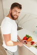 © Drobot Dean - Vertical image of smiling bearded man cuts vegetables on kitchen