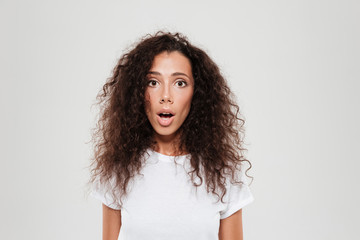 Wall Mural - Shocked curly woman looking at the camera