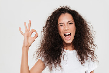 Poster - Pretty curly woman showing ok sign with open mouth