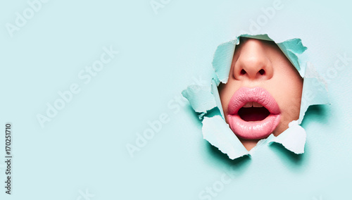 Fotografía Beautiful plump bright lips of pink color peep into the slit of colored paper