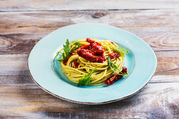 Homemade pasta spaghetti with pesto sauce and dried tomatoes. Copy space