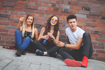 Wall Mural - Group of young friends sitting on street and talking