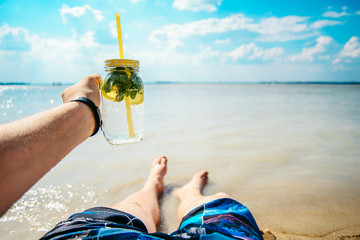 man holding glasses of mojito at the beach