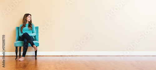 Fotografía Young latina woman sitting in a chair in a large interior room