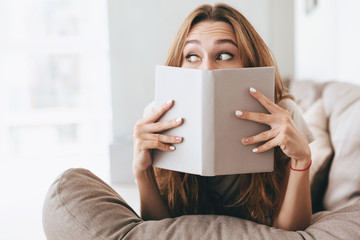 Wall Mural - Pretty lady covering face with book.