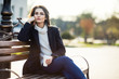 © GVS - Thoughtful beautiful woman with cup of coffee sitting on a bench in city street