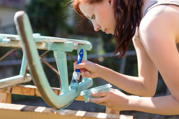 Diy im Garten, Frau streicht einen Holzschlitten in Shabby chic