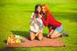 © T.Den_Team - Two young pretty women with red and dark hair relax on picnic and enjoy life. Women's friendship as it is. Sisters rest on nature on the green lawn. Inspire lady with good mood at beautiful autumn day
