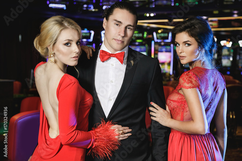 Cuadros en Lienzo Confident man and two beautiful women in the casino