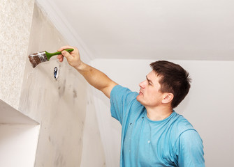 Wall Mural - worker painting wall with background glue for a wallpaper