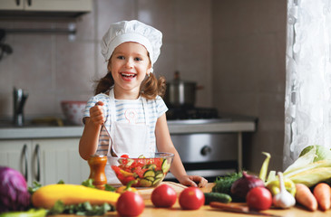 Poster - Healthy eating. Happy child girl prepares  vegetable salad in kitchen