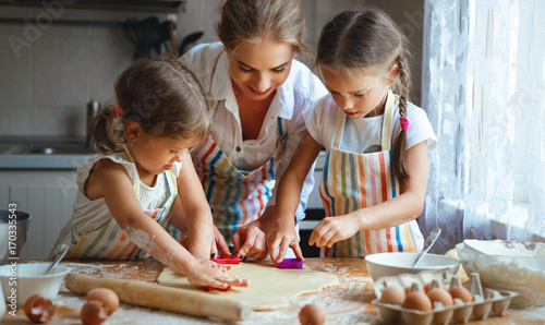 Fotomural Happy family mother and children twins bake kneading dough in kitchen