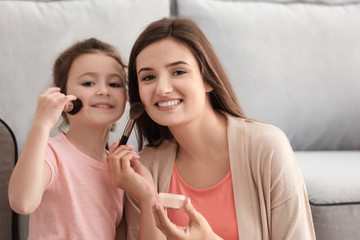 Sticker - Young woman and her little daughter applying makeup at home