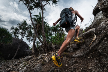 Woman hiker with backpack climbs steep rocky terrain