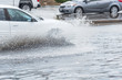 Splash by car as it goes through flood water after heavy rains of Harvey hurricane storm in Houston, Texas, US. Flooded city road with big puddle of water spray from the wheels of sedan car roaring by
