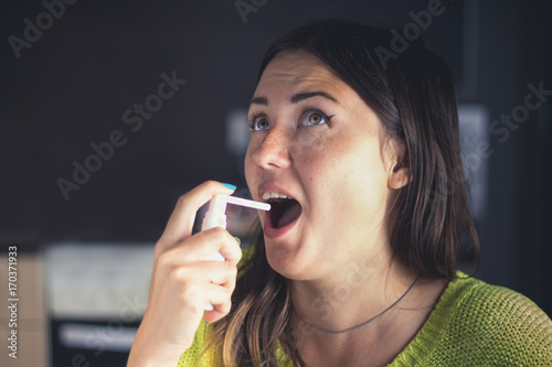Fotografie, Obraz The girl splashes in her mouth with a spray from the pain in her throat